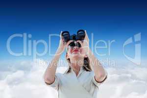 Composite image of businesswoman looking through binoculars