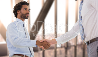 Composite image of young businessmen shaking hands in office