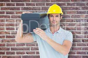 Composite image of confident worker carrying tool box on shoulde