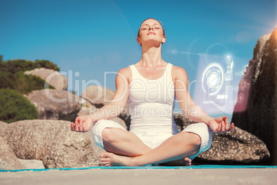 Composite image of blonde woman sitting in lotus pose on beach o
