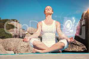 Composite image of blonde woman sitting in lotus pose on beach o