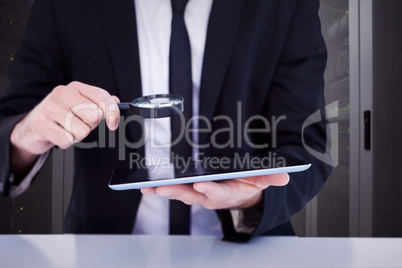 Composite image of businessman looking at his tablet through mag