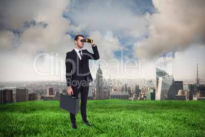 Composite image of businessman holding a briefcase while using b