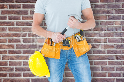Composite image of worker holding hammer over white background