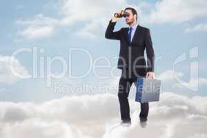 Composite image of businessman looking through binoculars holdin