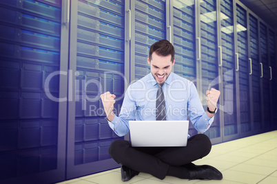 Composite image of businessman sitting with his laptop cheering