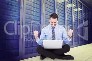 Composite image of businessman sitting with his laptop cheering