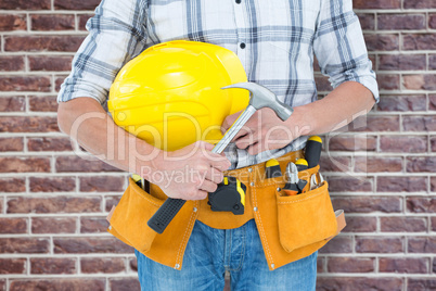 Composite image of technician holding hammer and hard hat