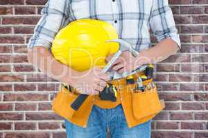 Composite image of technician holding hammer and hard hat