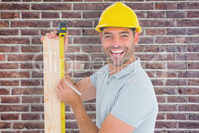 Composite image of construction worker using measure tape to mar