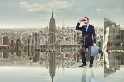Composite image of businessman looking through binoculars holdin