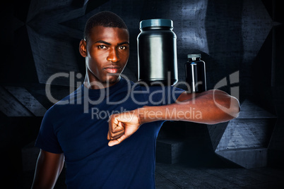 Composite image of fit man holding bottles with supplements on h
