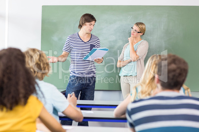 Student explaining notes besides teacher in class