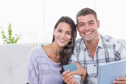 Happy couple shopping online on digital tablet using credit card