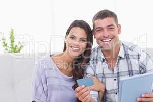 Happy couple shopping online on digital tablet using credit card