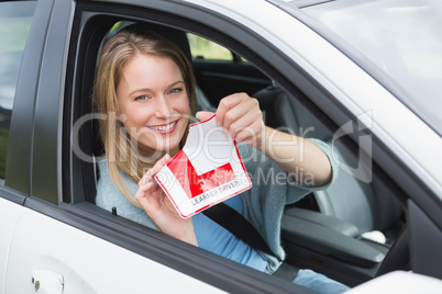 Learner driver smiling and tearing l plate