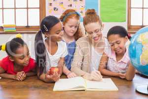 Cute pupils and teacher smiling at camera in classroom