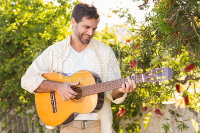 Happy man smiling at camera playing guitar