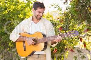 Happy man smiling at camera playing guitar