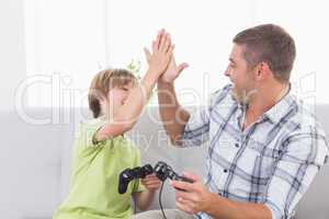 Father and son giving high-five while playing video game