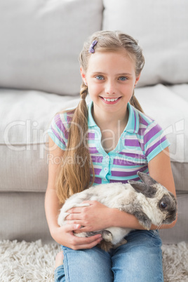 Cute girl holding rabbit in living area