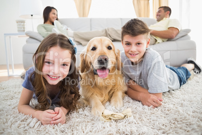 Siblings lying with dog while parents relaxing on sofa