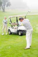 Golfer about to tee off with partner behind him