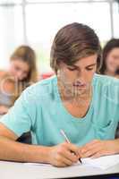 Male student writing notes in classroom