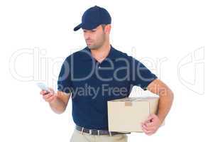 Delivery man using mobile phone while holding package