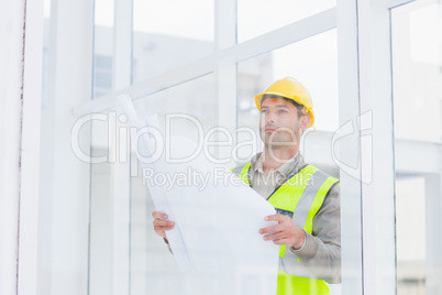 Thoughtful architect holding blueprint in office