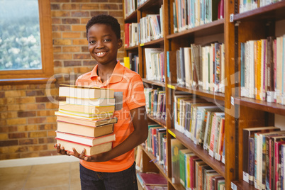 Portrait of cute boy carrying books in library