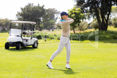 Female concentrating golfer teeing off