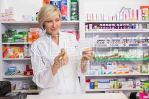 Smiling pharmacist looking at prescription and medicine