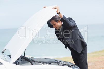 Stressed businessman looking at engine