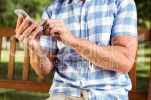 Man sitting on park bench with phone