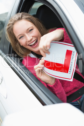 Learner driver smiling and holding l plate