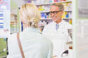 Senior pharmacist speaking with customer