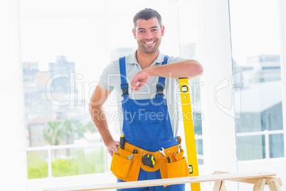 Carpenter in overalls with spirit level in office