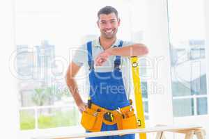 Carpenter in overalls with spirit level in office