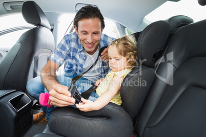 Father securing baby in the car seat