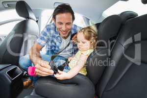 Father securing baby in the car seat