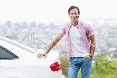 Smiling man standing next to his car