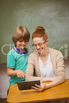 Teacher and boy using digital tablet in classroom