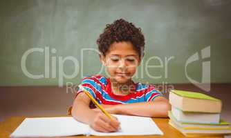 Little boy writing book in classroom