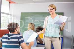 Teacher handing paper to student in class