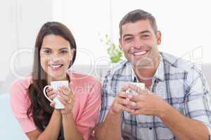 Happy couple holding coffee mugs at home