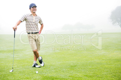 Cheerful golfer holding his club with hand on hip