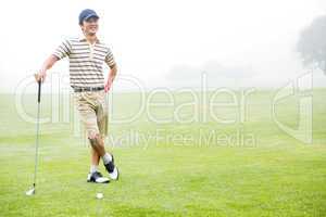 Cheerful golfer holding his club with hand on hip