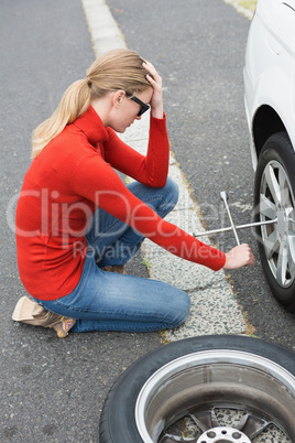 Annoyed woman trying to replace tire