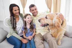 Family looking at Golden Retriever on sofa